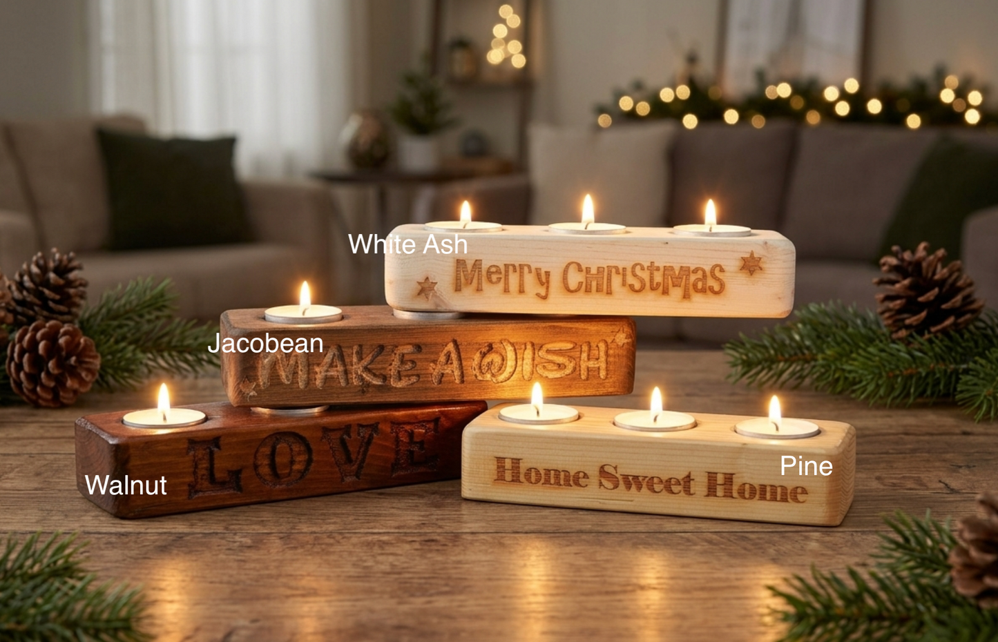Four rectangular wooden candle holders with lit tea light candles arranged on a wooden table in a cozy living room setting. The holders are labeled White Ash, Jacobean, Walnut, and Pine, with engraved holiday phrases including 'Merry Christmas,' 'MAKE A Wish,' 'LOVE,' and 'Home Sweet Home.