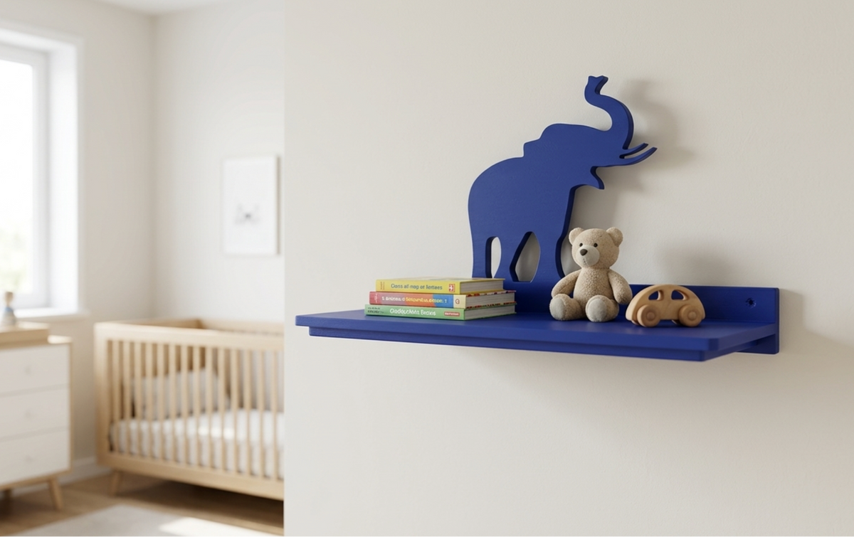 A blue wall-mounted elephant silhouette shelf in a softly lit nursery, styled with a blue, stacked books, a teddy bear, and a wooden toy car.