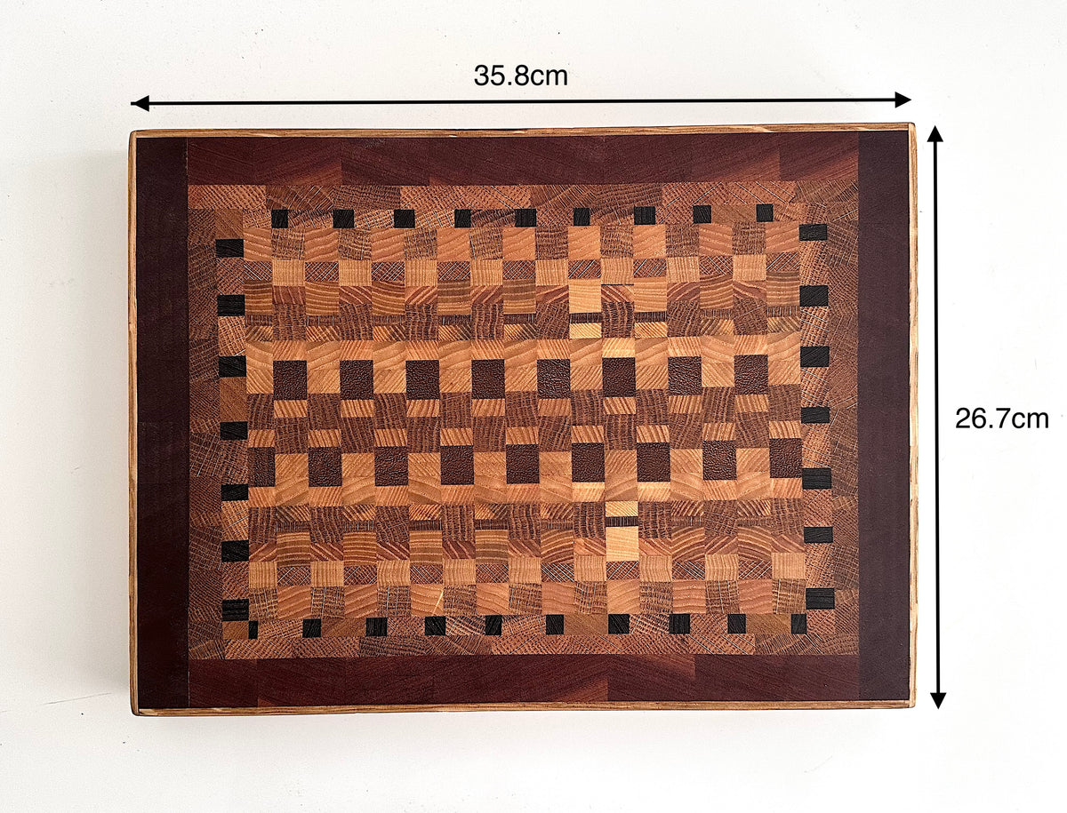 A rectangular wooden board with a geometric checkerboard pattern made from contrasting wood tones, shown from above on a white background with black dimension arrows and text indicating 35.8 cm by 26.7cm.